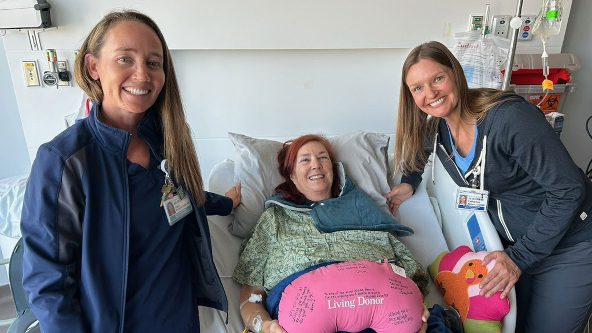 Mainquist in hospital bed and nurses on either side